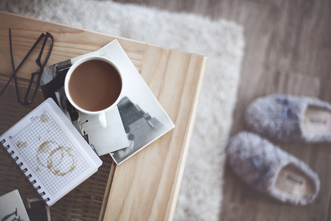 coffee on a coffee tablke with books and slippers on the ground